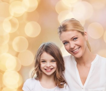 family, childhood, happiness and people - smiling mother and little girl over beige lights background