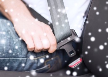 transportation, safety, people and vehicle concept - close up of man fastening seat belt in car