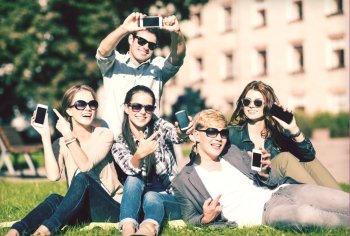 education, technology, internet, summer holidays, social networking and teenage concept - group of teenagers with smartphones