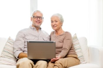family, technology, age and people concept - happy senior couple with laptop computer at home