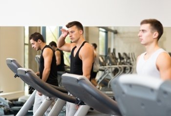 sport, fitness, lifestyle, technology and people concept - group of men exercising on treadmill in gym
