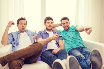 friendship, technology and home concept - smiling male friends with remote control at home