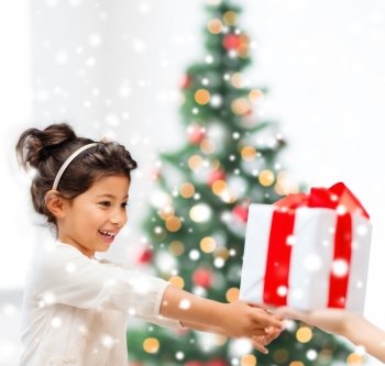 holidays, christmas, childhood and people concept - smiling little girl with gift box at home