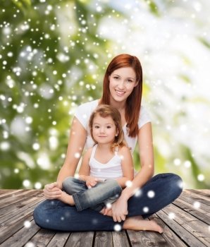 childhood, parenting and people concept - happy mother with little girl over wooden floor and green plants background