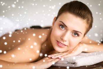 beauty, health, people and spa concept - beautiful woman in spa salon getting hot stones massage