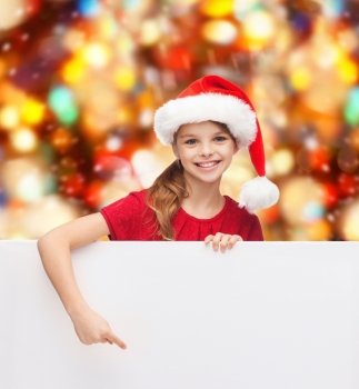 christmas, holidays, people, advertisement and sale concept - happy little girl in santa helper hat with blank white board over red lights background