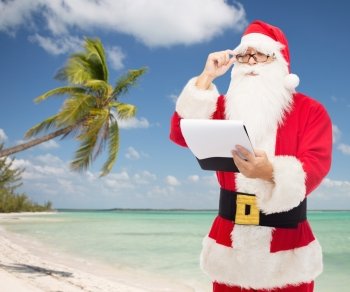 christmas, holidays, travel and people concept - man in costume of santa claus with notepad over tropical beach background