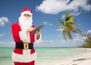 christmas, holidays, technology, travel and people concept - man in costume of santa claus with tablet pc computer over tropical beach background