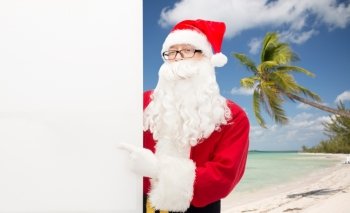 christmas holidays, advertisement, gesture, travel and people concept - man in costume of santa claus pointing finger to white blank billboard over tropical beach background