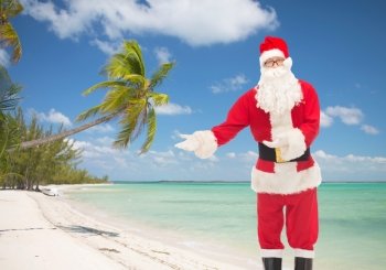 christmas, holidays, gesture, travel and people concept - man in costume of santa claus over tropical beach background