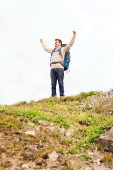 adventure, travel, tourism, hike and people concept - smiling man with backpack raising hands outdoors