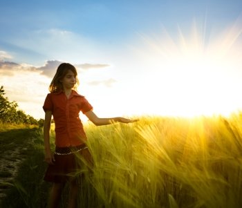 Teenage girl in wheat field likes a crop