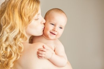 A natural blonde caucasian mother kissing happy baby