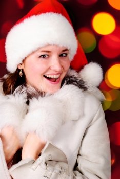 Happy girl in santa hat over blurred illuminated background