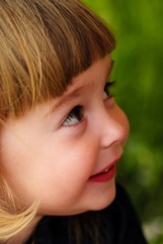 Little girl’s face with hands and smile. Close up soft portrait on nature. Shalllow DOF. Focus on right eye