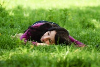 Brunette girl take pleasure and rest on the grass. Close up face
