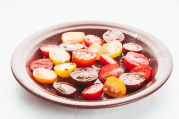 Various types of cherry tomatoes on the plate. Tomato salad on white table