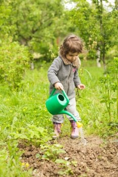Little kid with watering can in the garden