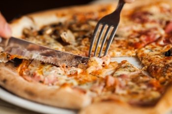 Man eats pizza. Close up pizza with fork and knife