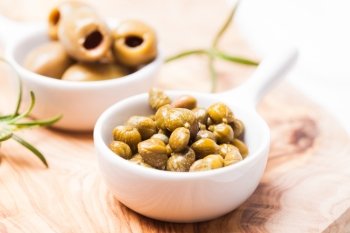 Marinated capers - in a white saucer on a board