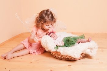 Little girl with her newborn sister in a basket