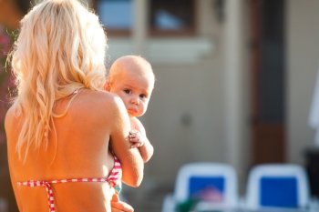 Pretty young mom with baby at the swimming pool. Mom and baby rest