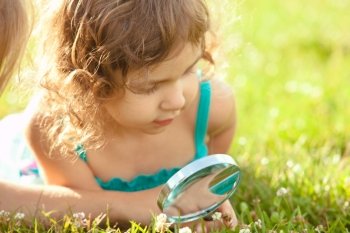 Kid plays with magnifying glass in the garden. Kid with magnifying glass 