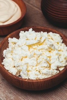 cottage cheese or curd in a wooden bowl. The cottage cheese