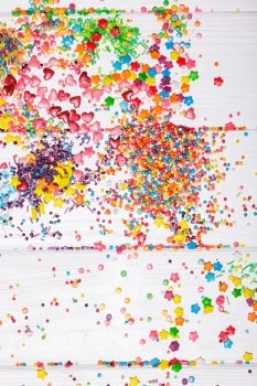 Various color sprinkles scattered on white wooden table. color sprinkles