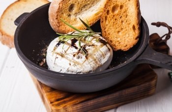 Baked camembert with herbs and spices on the pan. Baked camembert
