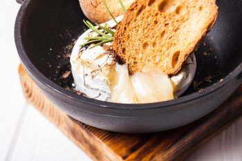 Baked camembert with herbs and spices on the pan. Baked camembert