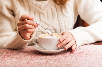 Woman&#39;s hands holding mix cappuccino on the table. Close-up