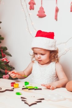 Adorable girl is painting wooden Christmas figurines. Handmade Christmas decorations