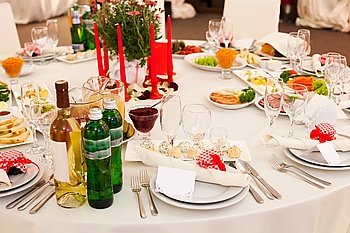 Table set for a wedding reception in white and red colors with gift on a plate. Wedding table decoration