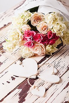 Luxury bouquet of roses lying on a wooden board and wooden hearts. Bouquet of roses