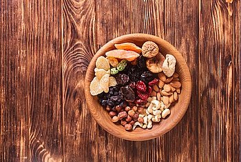 Dry fruits and nuts in bowl on wooden table. Copy space background - close up healthy sweets. Dry fruits and nuts 