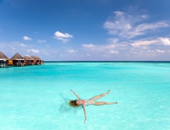 Young woman smiles, swiming in ocean, Maldives