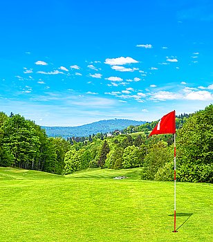 Green golf field and blue sky. Golf course with red flag. Spring landscape