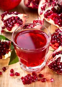 glass of pomegranate  juice with fresh fruits on wooden table