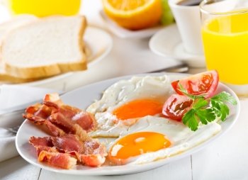 Fried eggs with bacon and vegetables