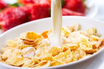 Breakfast with milk pouring in corn flakes 