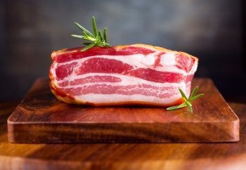 Smoked bacon with rosemary on wooden table