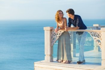 Couple posing on a balcony with ocean in the background