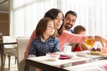 Young latin family having breakfast with kids