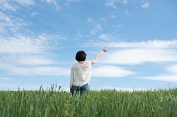 Woman poiting up to copyspace in green field