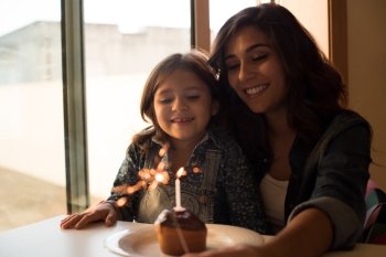 Mother and daughter celebrating birthday with cupcake and sparklers