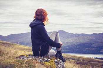 Young woman sitting in the mountains at sunrise