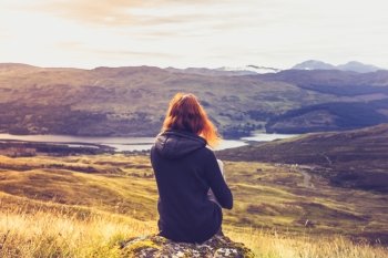 Young woman sitting in the mountains at sunrise