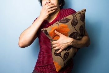 Scared young man clutching a cushion