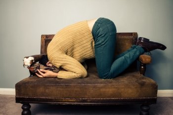 Young man hiding his head on sofa
